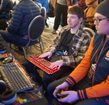 man using video game control pad beside man using computer keyboard sitting and playing video games