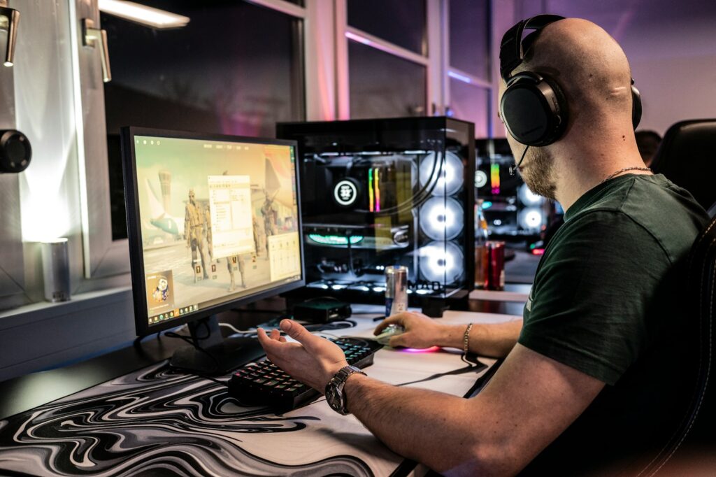 A man sitting in front of a computer monitor wearing headphones